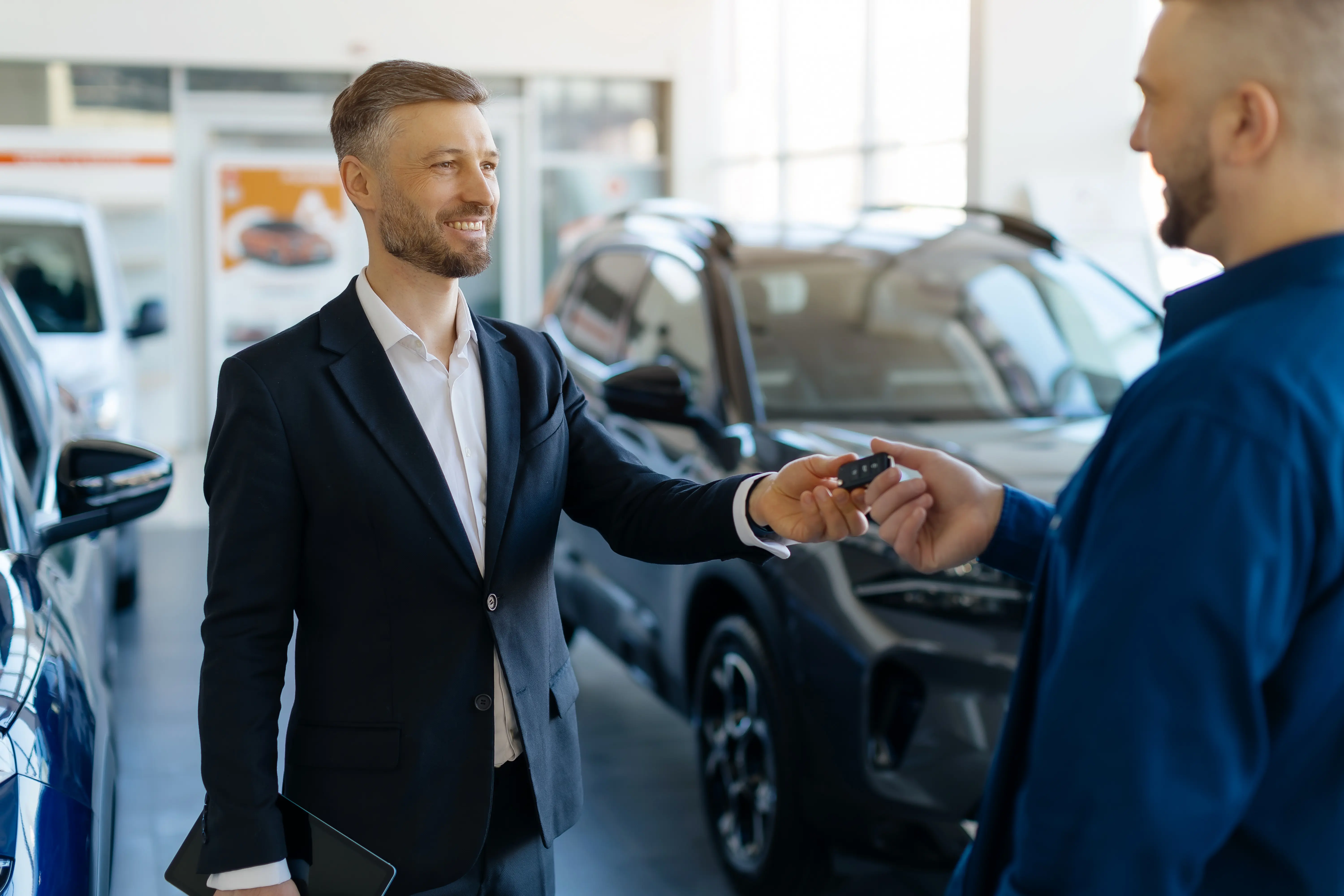 A dealership specialist handing vehicle keys to a customer